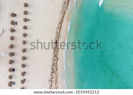 Ocean shore. Turquoise water, calm. White sand and a large row of beach umbrellas. High angle view. Drone shooting. There are no people in the photo. Wallpaper. Background. Texture.