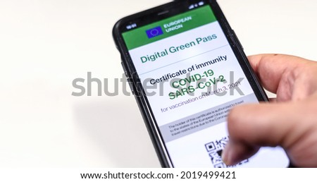 The digital green pass of the european union with the QR code on the screen of a mobile held by a hand on a white background. Immunity from Covid-19. Permit to travel without restrictions.