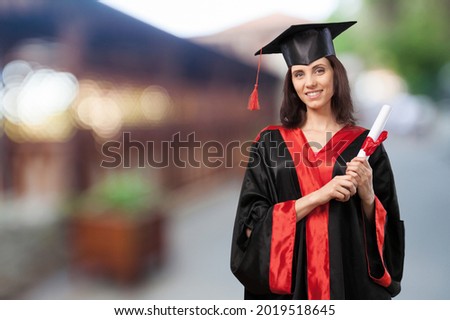 Happy student university graduate in traditional costume standing and holding diploma