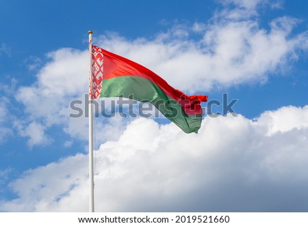 Flag of Belarus on flagpole waving against blue sky