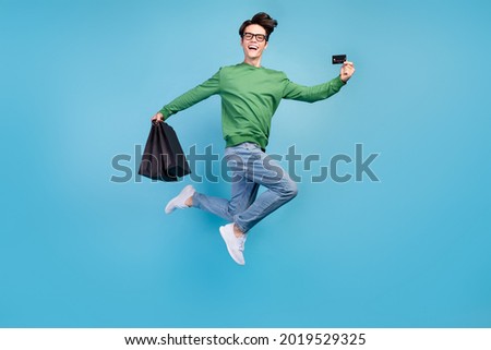 Full length body size photo guy jumping high showing credit card on shopping isolated pastel blue color background