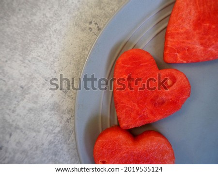 hearts cut from red urgent watermelon lie on a gray plate close up. view from above