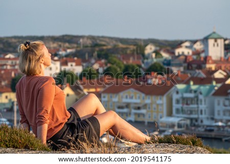 Smiling Caucasian Woman sunlit Enjoying Sunset over Swedish Summer party Island and Village Marstrand, Near Gothenburg and Sweden West Coast. Royalty-Free Stock Photo #2019541175