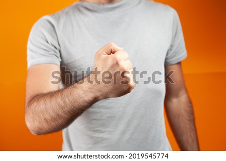 man shows fist on orange background