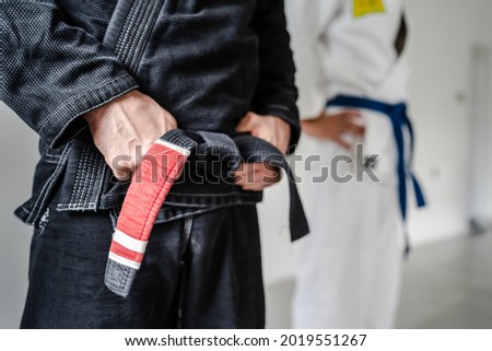 Side view of hand of unknown caucasian man in kimono gi standing while holding black bjj belt brazilian jiu jitsu concept copy space Royalty-Free Stock Photo #2019551267