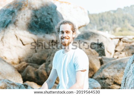 Young man smiling to camera during a sunny day, happiness concept, beach and holiday, reflection and yoga concepts