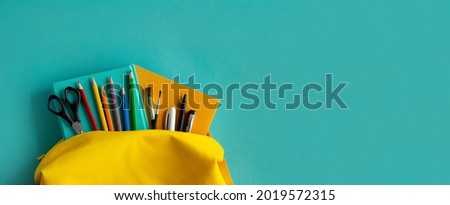 Backpack and school supplies: notepad, pens, scissors, book, watch on blue paper background Royalty-Free Stock Photo #2019572315