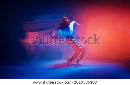 Dancing female standing on tiptoe in colourful neon studio light. Long exposure. Contemporary hip hop dance Royalty-Free Stock Photo #2019586109