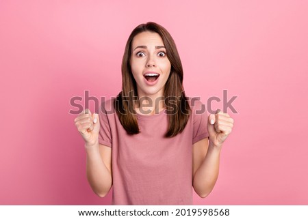 Photo of astonished brunette millennial lady hands fists yell wear pink t-shirt isolated on color background
