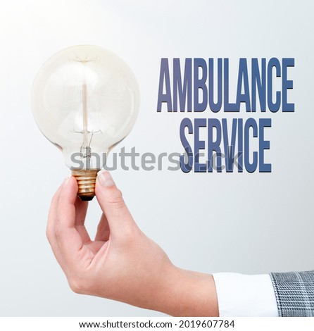 Sign displaying Ambulance Service. Business overview emergency response wing of the National Health Service Hand holding lamp showing or presenting new technology ideas