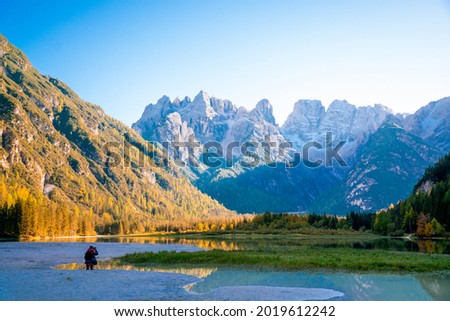 Breathtaking views of the alps. Travel photographer takes pictures of the mountain landscape. A tourist is filming with a tripod. A majestic lake in the alpine mountains.