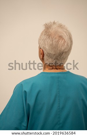 Rear view of a medical doctor or nurse glancing at a white wall