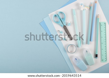 A frame of school supplies in pastel colors on a light blue background, space for text. Back to school. It was flat.