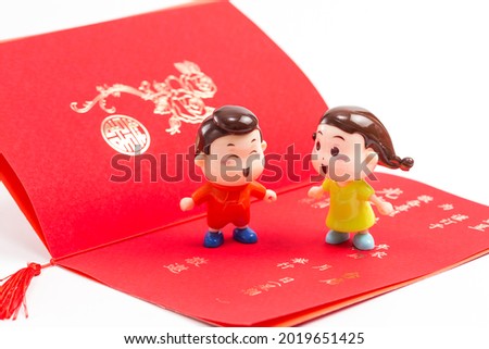 Two dolls in front of a wedding invitation（Translation:sent, scheduled in, a certain year, a certain month, a wedding, welcome,double happiness,address）