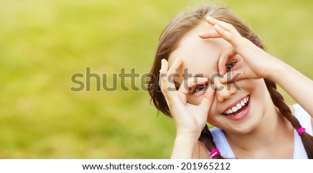 portrait of a cheerful girl who portrays glasses hands, over green background