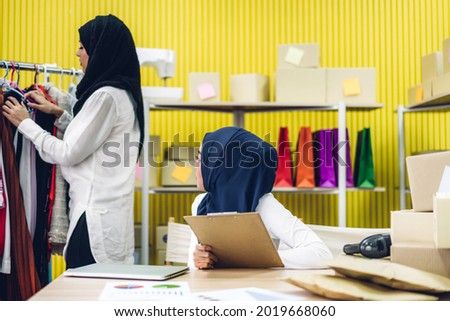 Muslim two asian woman freelancer sme business online shopping working and checklist order with cardboard box on table at home - Business online shipping and delivery concept