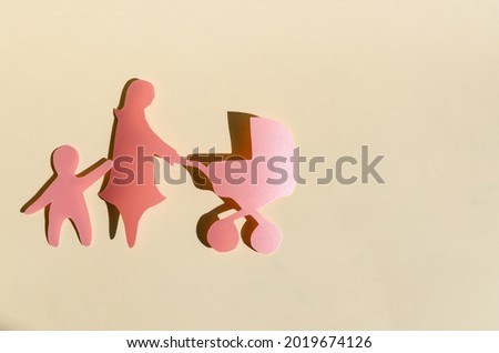 Cardboard figures of a mother with a stroller for a child on a colored background. The concept of family relations adults and children copy space