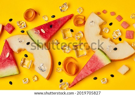 Fruit mix with slices of watermelon and melon next to ice cubes on a yellow background. Bright advertising of exotic tastes. Top View