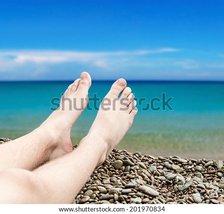 man's legs on the sand beach on a background of a sea landscape
