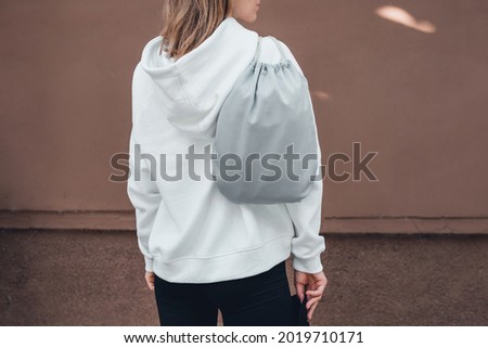 Grey drawstring pack template, mockup of bag for sport shoes on woman's shoulder, back view. Lifestyle, cropped. Royalty-Free Stock Photo #2019710171