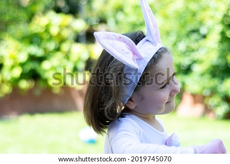 
little girl in a bunny costume is having a picnic in the garden of her house.
