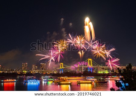 Aerial Skyline of Rainbow Bridge  at night time with a lot of lighten boats in the river and spectacular winter fireworks.
