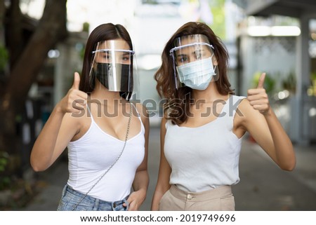 women recommend wearing both face mask and face shield with thumb up gesture, double layer covid-19 virus protection