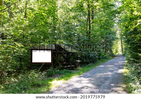 Advertising billboard panel for a mockup. Blank template for an ad next to a hiking trail in the forest. Space for an advertising billboard in nature. 
