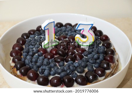 candles on a cherry cake in the form of numbers 13 close-up