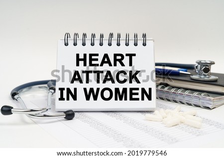 Medicine and health concept. On the table is a stethoscope, a diary and a notebook with the inscription - Heart Attack in Women