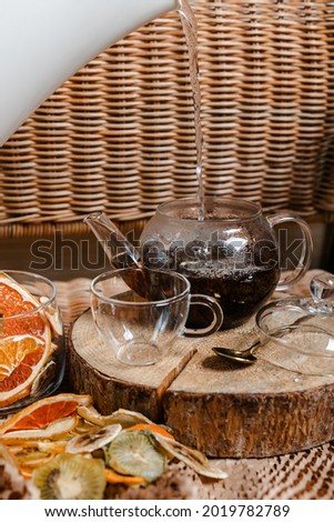Organic dried fruits. Homemade dehydrated fruit chips in a glass form. The concept of healthy eating. dried apples, orange, grapefruit, kiwi, banana top view. A glass teapot with tea on a log.