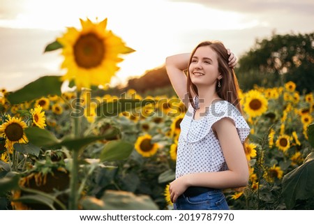 Cute attractive young girl walk through yellow bouquet blooming sunflower field outdoors sunset warm nature background. Woman stopped while travel on weekend copyspace. Summer holiday relax