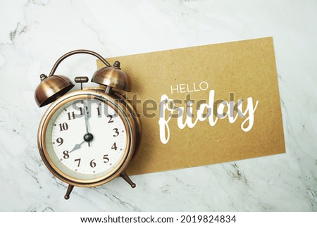 Hello Friday typography text on paper card with alarm clock on marble background