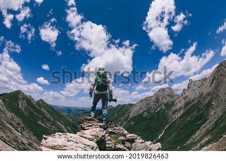 Successful woman hiker with camera on high altitude mountain top