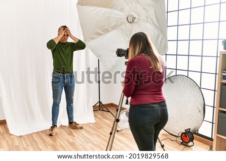Young man at photography studio suffering from headache desperate and stressed because pain and migraine. hands on head. 