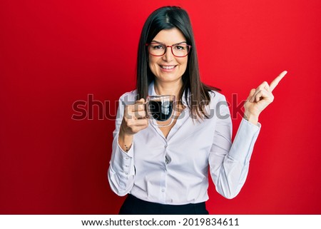 Young hispanic woman wearing business style drinking cup of coffee smiling happy pointing with hand and finger to the side 