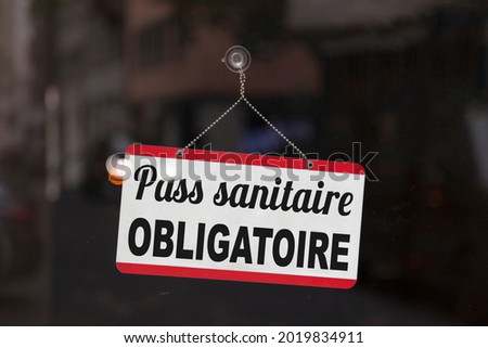 Close-up on a red and white sign in a window with written in French "Pass sanitaire obligatoire", meaning in English "Compulsory health pass". Royalty-Free Stock Photo #2019834911