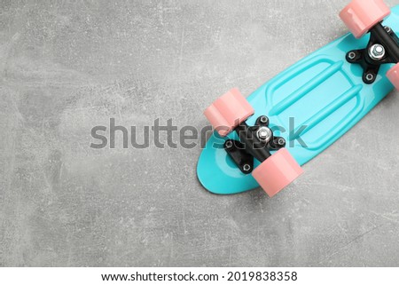 Turquoise skateboard on grey stone background, top view. Space for text