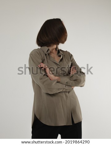  Girl wear black classic pants, and dark grey shirt. Fashion studio portrait of young elegant woman. Fashion portrait, look book and catalogue style. Woman looks proud and arrogant.