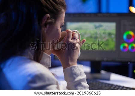 Focused editor retoucher editing color grade on professional computer sitting at desk in creative office at midnight. Freelancer video editor start up new movie project processing audio film montage.