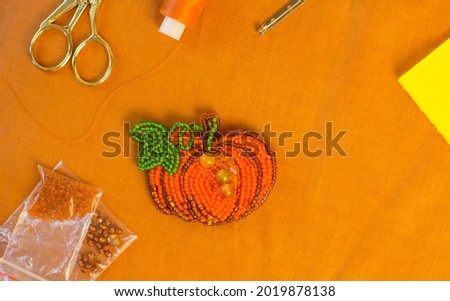 DIY present for halloween and thanksgiving day. Handmade beaded pumpkin. Jewelry designer making brooch with beads.
