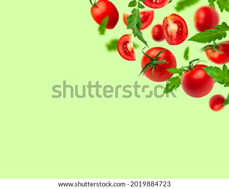 Creative food concept. Flying red ripe juicy tomatoes and green leaves on green background. Healthy vegan organic food, vegetable, cherry tomatoes, summer, harvesting. Tomatoes pattern
