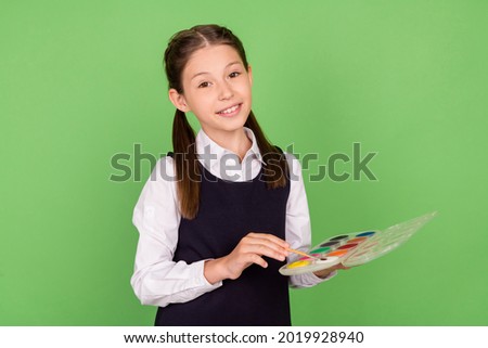 Photo of young school girl happy positive smile draw picture artwork lesson isolated over green color background