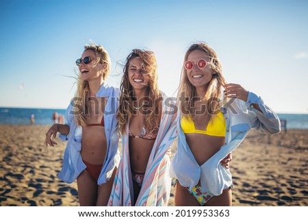 Group of happy young women walking on a beach. 