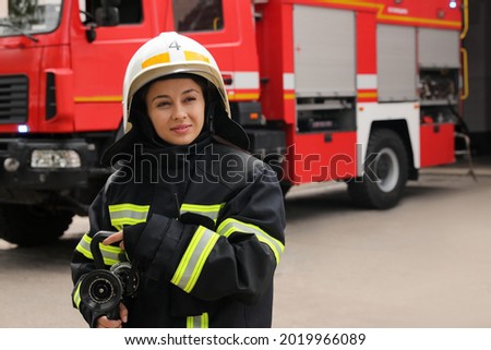 Firefighter in uniform with high pressure water jet near fire truck outdoors