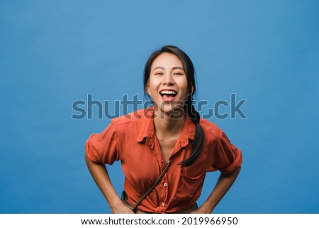 Young Asia lady with positive expression, smile broadly, dressed in casual clothing and looking at camera over blue background. Happy adorable glad woman rejoices success. Facial expression concept.