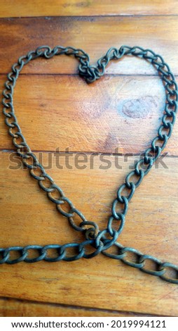 Old and rusty iron chain on a wooden background.