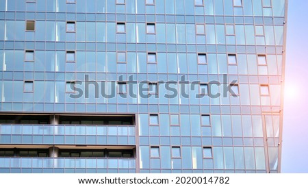 Futuristic facade of a modern office building clad in glass. Glass cladding panels and windows of modern building. An office building with geometry and perspective.