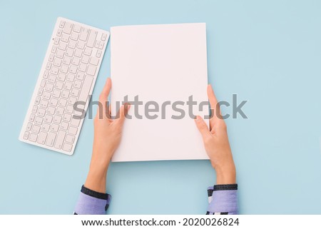 Female hands, blank magazine and keyboard on color background