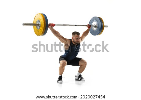 Full length portrait of man in sportswear exercising with a weight isolated on white background. Fit young muscular caucasian model with barbell training at abstract gym. Sport, weightlifting concept Royalty-Free Stock Photo #2020027454